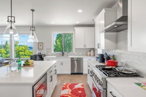 Una cocina moderna con armarios blancos, electrodomésticos de acero inoxidable y una isla grande con un tapete de diseño rojo y blanco.