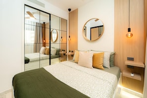 Ein modernes Schlafzimmer mit einem großen Bett, einem Spiegel und einem Nachttisch.