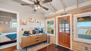 A room with a bed, a wooden dresser, a ceiling fan, a door labeled 'FLORIDA,' and a view of the water outside. - 3-BR Waterfront, Sebastian Inlet Views, Private Dock & Daily Wildlife Sightings (Micco)