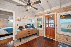 Ein Zimmer mit einem Bett, einem Holzschrank, einem Deckenventilator, einer Tür mit der Aufschrift 'FLORIDA' und Blick auf das Wasser.