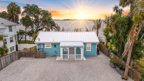 A small house with a white roof, a porch, and a view of the water. - 3-BR Waterfront, Sebastian Inlet Views, Private Dock & Daily Wildlife Sightings (Micco)