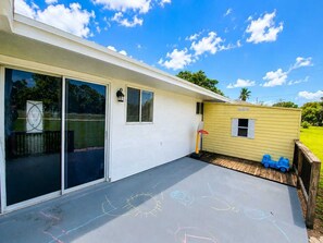 A house with a covered patio, a garage with a sliding door, and a small yellow shed.