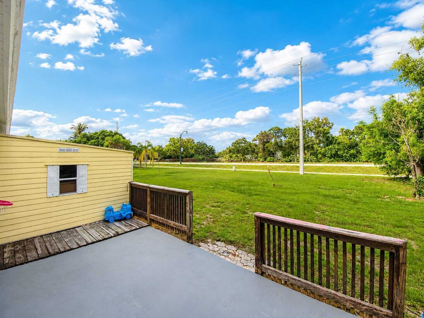 A house with a small deck, a grassy yard, and a clear blue sky.