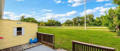 A house with a small deck, a grassy yard, and a clear blue sky.