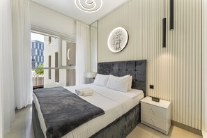 Ein modernes Schlafzimmer mit Bett, Nachttischen, einer Fensterbank und einer Wanduhr. Vor dem Fenster hängen Vorhänge.