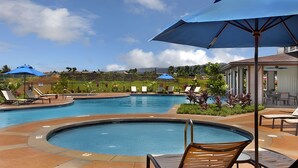 A pool area with lounge chairs and umbrellas, surrounded by greenery and a view of distant mountains. - Ocean View 6BR, 2 Condos for 16 in Koloa! (Koloa)
