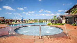 A swimming pool with multiple water jets, surrounded by lounge chairs and a landscaped garden. - Ocean View 5BR, 2 Condos for 14 in Koloa! (Koloa)