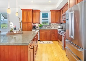 A modern kitchen with wooden cabinets, stainless steel appliances, and a large island. - Poipu, Pili Mai, Spacious 6 BR, Ocean View, Sleeps 16 (Koloa)