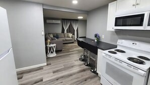 Une cuisine compacte avec des appareils électroménagers blancs, un coin repas avec un canapé et une petite table d’appoint.