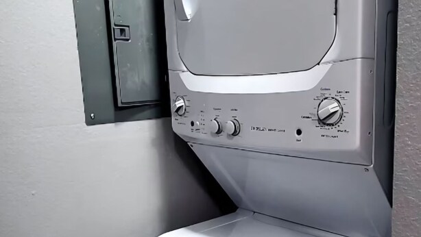 Une machine à laver compacte et moderne, dotée d’un panneau de commande avec plusieurs boutons et molettes, probablement pour différents programmes de lavage.