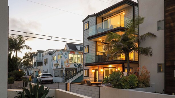 Un edificio residencial de varios pisos con un balcón, una escalera y una entrada bien iluminada.