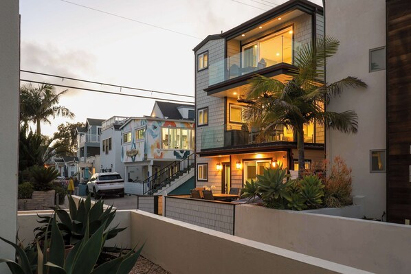 Un edificio residencial de varios pisos con un balcón, una escalera y una entrada bien iluminada.
