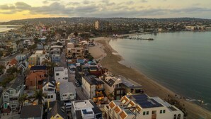 Un paisaje urbano costero con playa, edificios residenciales y un muelle.