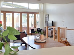 Ein Wohnzimmer mit Essbereich, einer Treppe und Blick ins Freie.