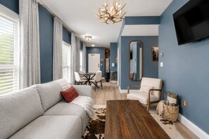 Een moderne woonkamer met een bank, salontafel en een aan de muur bevestigde televisie.