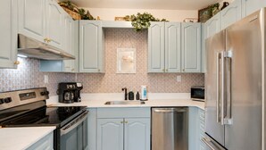 Una cocina con armarios azul claro, electrodomésticos de acero inoxidable, cafetera y lavavajillas.