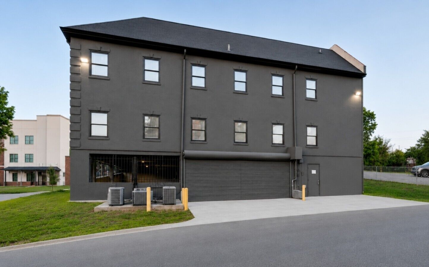 A modern building with a flat roof, multiple windows, and a garage door.