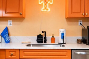 A kitchen with orange cabinets, a sink, a coffee maker, and a neon sign. - Game Day Getaway | Vols-Themed Stay Near Vanderbilt (Nashville)