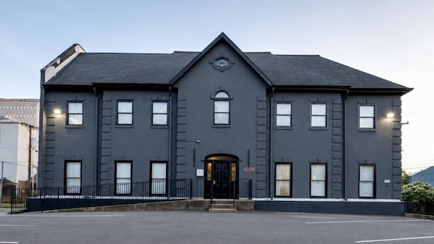 En stor, mørk bygning med en symmetrisk facade, mange vinduer og en central indgang.
