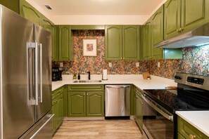 A kitchen with green cabinets, a stainless steel refrigerator, a dishwasher, and a stove. - Relaxing Bohemian Retreat | Walk to Sportsplex (Nashville)