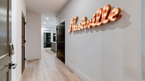 Een gang met een modern interieur, een verlicht naambord met 'Nathalie' en een deur naar een kamer.