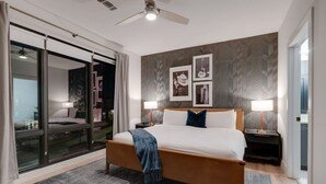 Een moderne hotelkamer met een groot bed, een plafondventilator en uitzicht door een glazen deur.