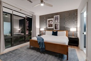 A modern hotel room with a large bed, a ceiling fan, and a view through a glass door. - Two Kings on Top Floor w/ Pool & Patio (Nashville)