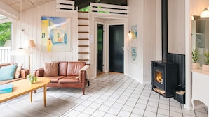 A cozy living room with a fireplace, a sofa, a coffee table, and a painting on the wall. - 4 Star Holiday Home in Glesborg (Glesborg)