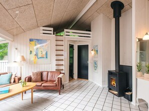 A cozy living room with a fireplace, a sofa, a coffee table, and a painting on the wall. - 4 Star Holiday Home in Glesborg (Glesborg)