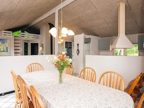 A dining area with a table set for six, surrounded by wooden chairs, a vase of flowers, and pendant lighting. - 4 Star Holiday Home in Glesborg (Glesborg)