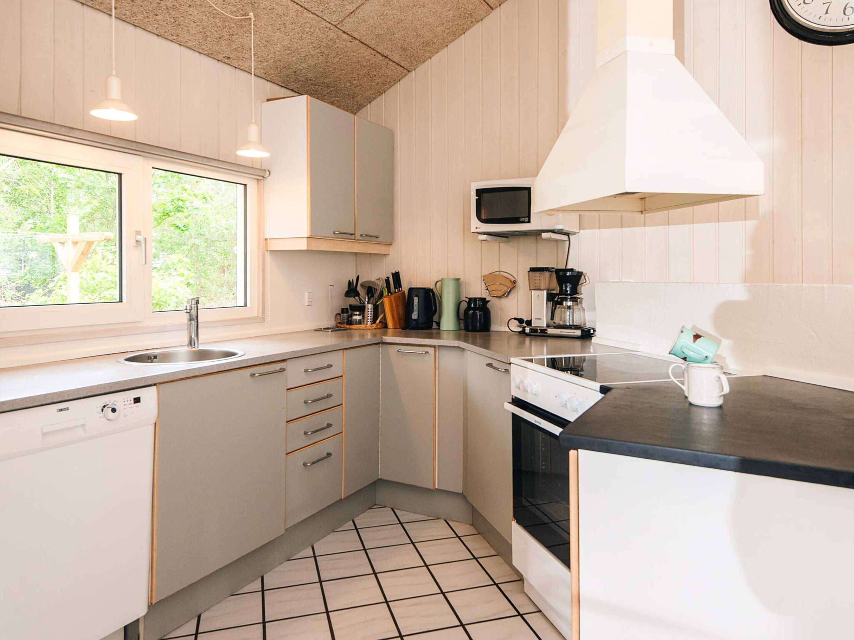 A modern kitchen with a window, stainless steel appliances, and a tiled floor.