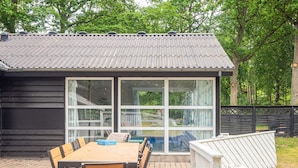 A covered patio with a table and chairs, a sliding glass door, and a fenced area. - 4 Star Holiday Home in Glesborg (Glesborg)