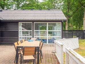 A covered patio with a table and chairs, a sliding glass door, and a fenced area. - 4 Star Holiday Home in Glesborg (Glesborg)