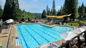 A swimming pool with clear blue water, surrounded by trees and shaded by yellow umbrellas. - Enjoy a serene 3 bedroom cabin located in Blue Lake Springs, Arnold. (Arnold)