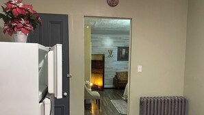 Ein Durchgang zu einem Wohnzimmer mit Kamin, Heizkörper und einer Pflanze auf einer Ablagefläche.
