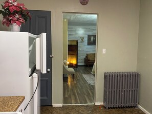 Ein Durchgang zu einem Wohnzimmer mit Kamin, Heizkörper und einer Pflanze auf einer Ablagefläche.