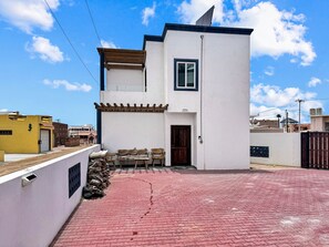 A two-story building with a flat roof, a small window, and a door. - Cozy 1-bedroom, sleeps 4, AC, Electric Vehicle Charger, Courtyard, BBQ grill (Bahía la Choya)