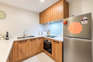 Eine moderne Küche mit Holzausstattung, einem Edelstahlkühlschrank und einem eingebauten Backofen.