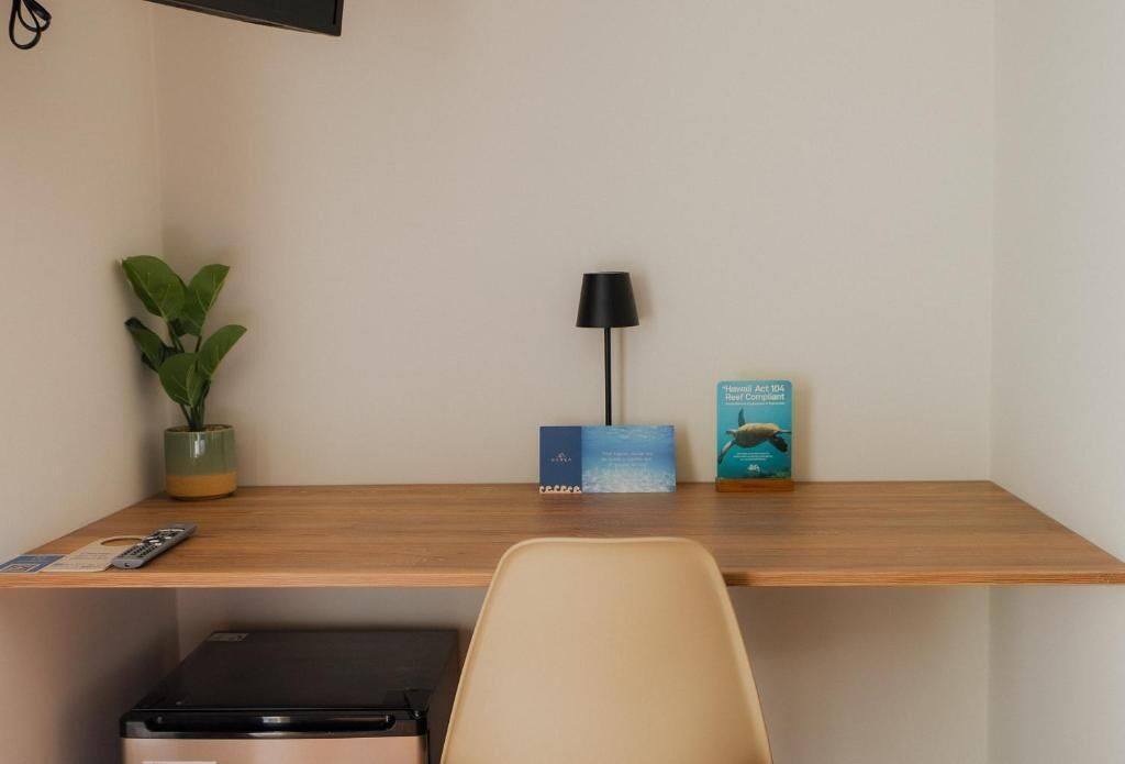 Un escritorio de madera con una planta, una lámpara y libros.
