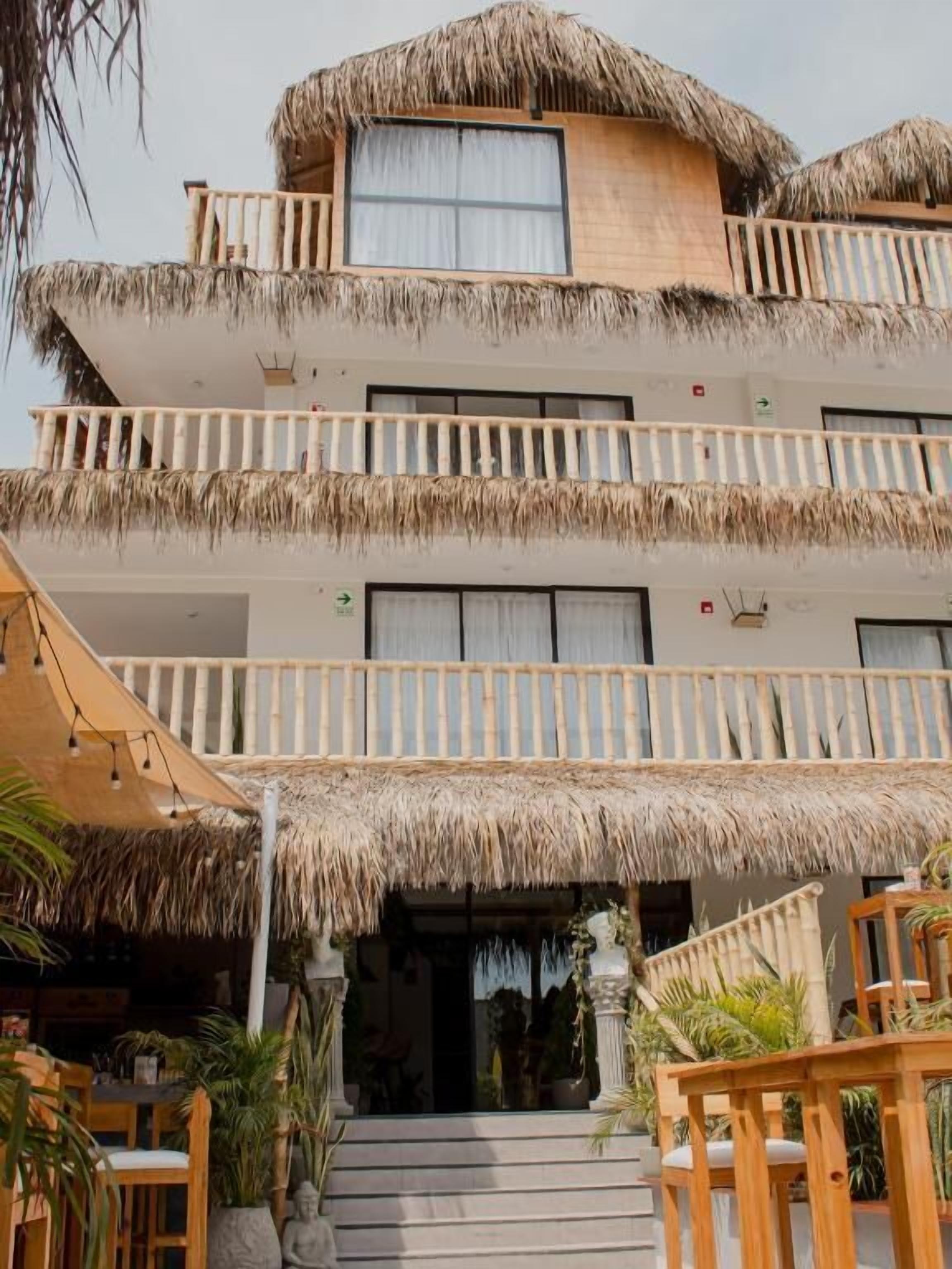 Un edificio de varios pisos con techo de paja, balcones y una escalera que conduce a la entrada.