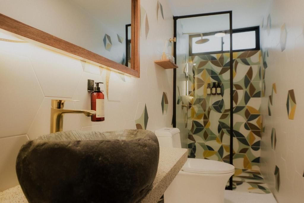 Un baño con lavabo de piedra, inodoro, ducha y espejo.
