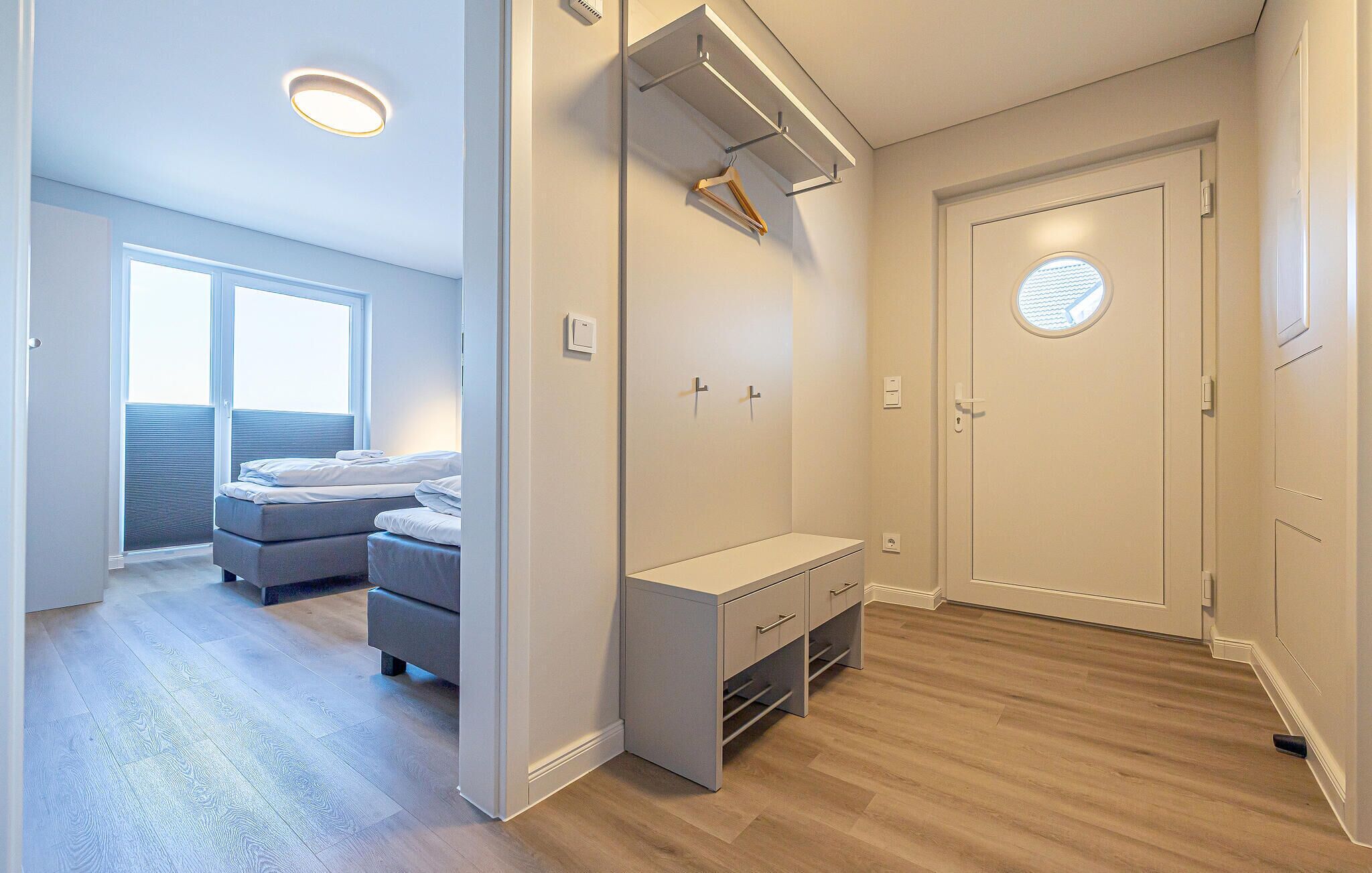 A modern bedroom with a bed, a desk, and a wardrobe.