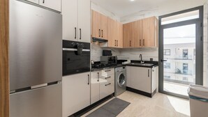 A modern kitchen with stainless steel appliances, wooden cabinets, and a large window. - Luxury apartment, Agadir bay, pool&fibre (Agadir)