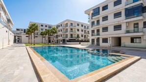 A modern building with a swimming pool, palm trees, and a clear sky. - Luxury apartment, Agadir bay, pool&fibre (Agadir)