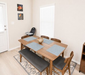 Een eethoek met een houten tafel, vier stoelen, een bank en een decoratieve schaal.