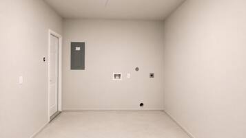 Ein schlichter Raum mit einer Tür, einem Projektor und einem kleinen, an der Wand befestigten Schrank.