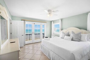 A bedroom with a bed, a nightstand, a ceiling fan, a door, and a view of the ocean through a sliding door. - Ocean Front Home, Gorgeous Views, Beach Gear, BBQ (St. Augustine)