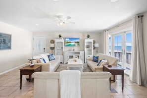 A living room with a large TV, two sofas, a coffee table, and a balcony with a view. - Ocean Front Home, Gorgeous Views, Beach Gear, BBQ (St. Augustine)