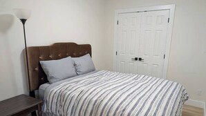 Une chambre à coucher avec un lit, une table de chevet, une lampe et une porte blanche.