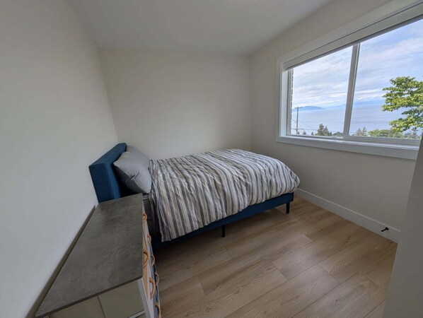 Un dormitorio con cama, ventana y suelo de madera.